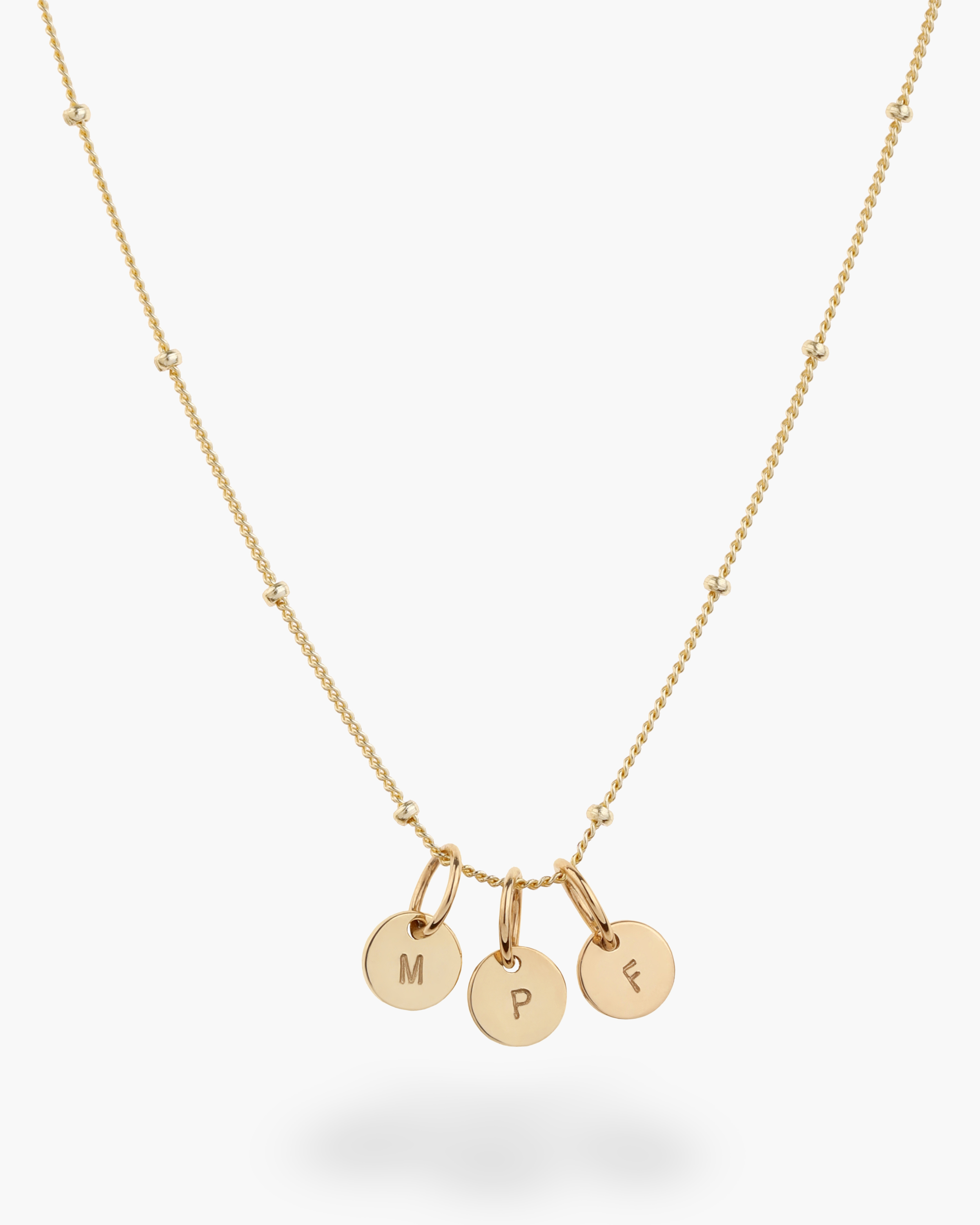 Gold necklace with three round solid gold pendants on a white background
