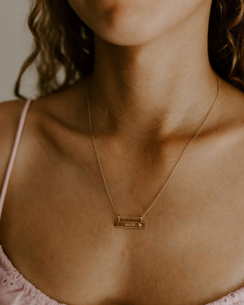 Personalised engraved bar necklace with heart pendant, worn as a keepsake gift and everyday meaningful jewellery piece.