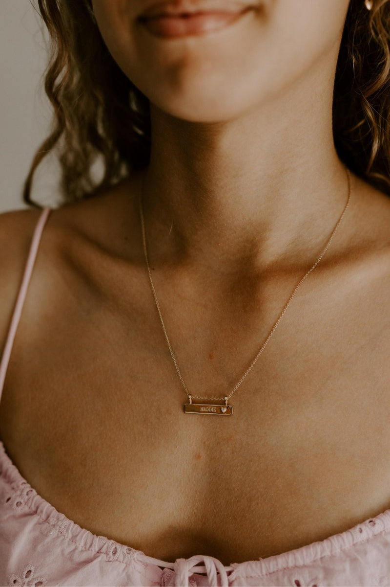 Pink Darling Bar necklace is worn by a young girl and the pendant has been personalised with engraving to feature her name on it.
