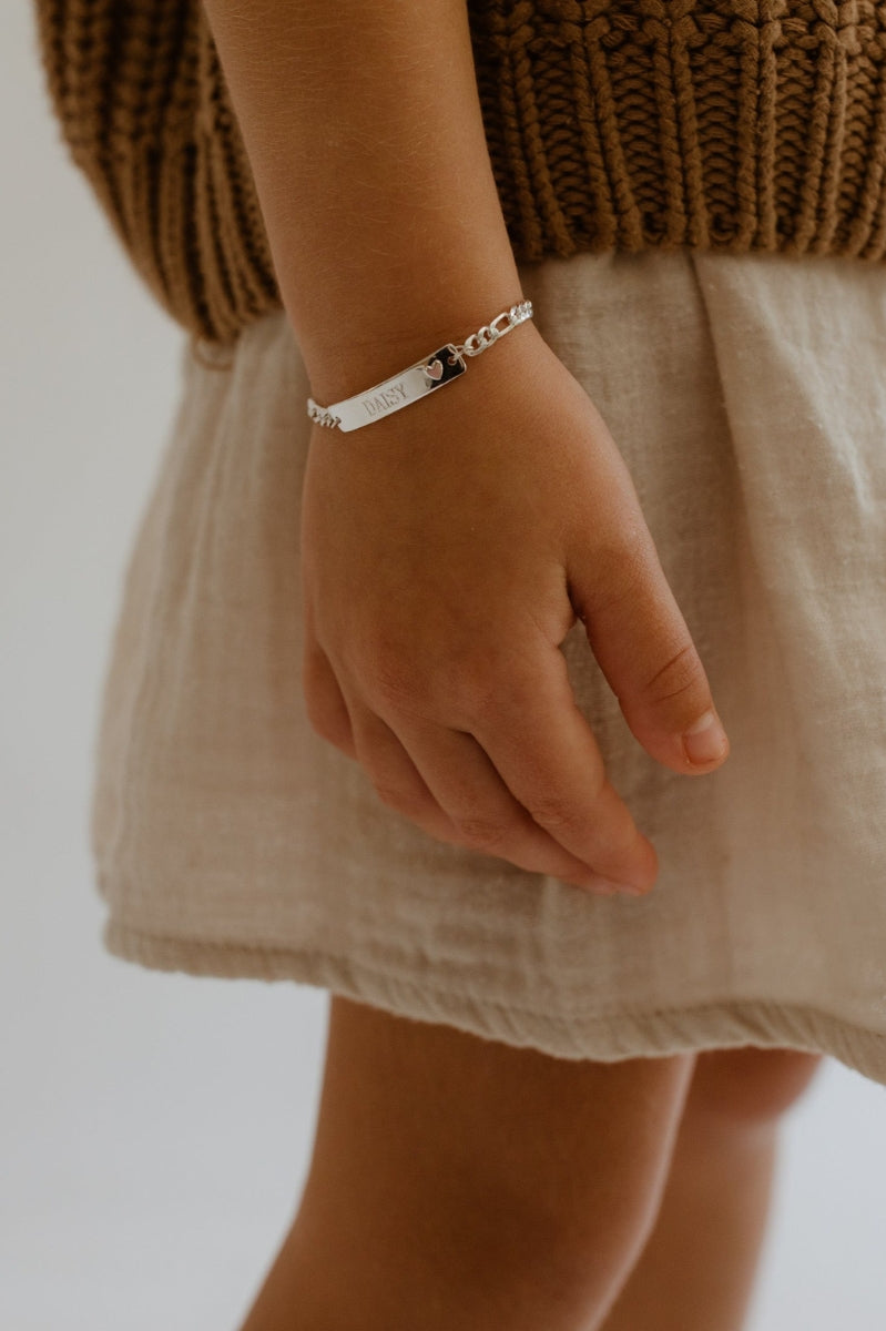 A child wears the Pink Darling Bracelet with the engraving 'DAISY' on the front of the ID Bracelet.  She is wearing the child size by Bluebird Jewellery.