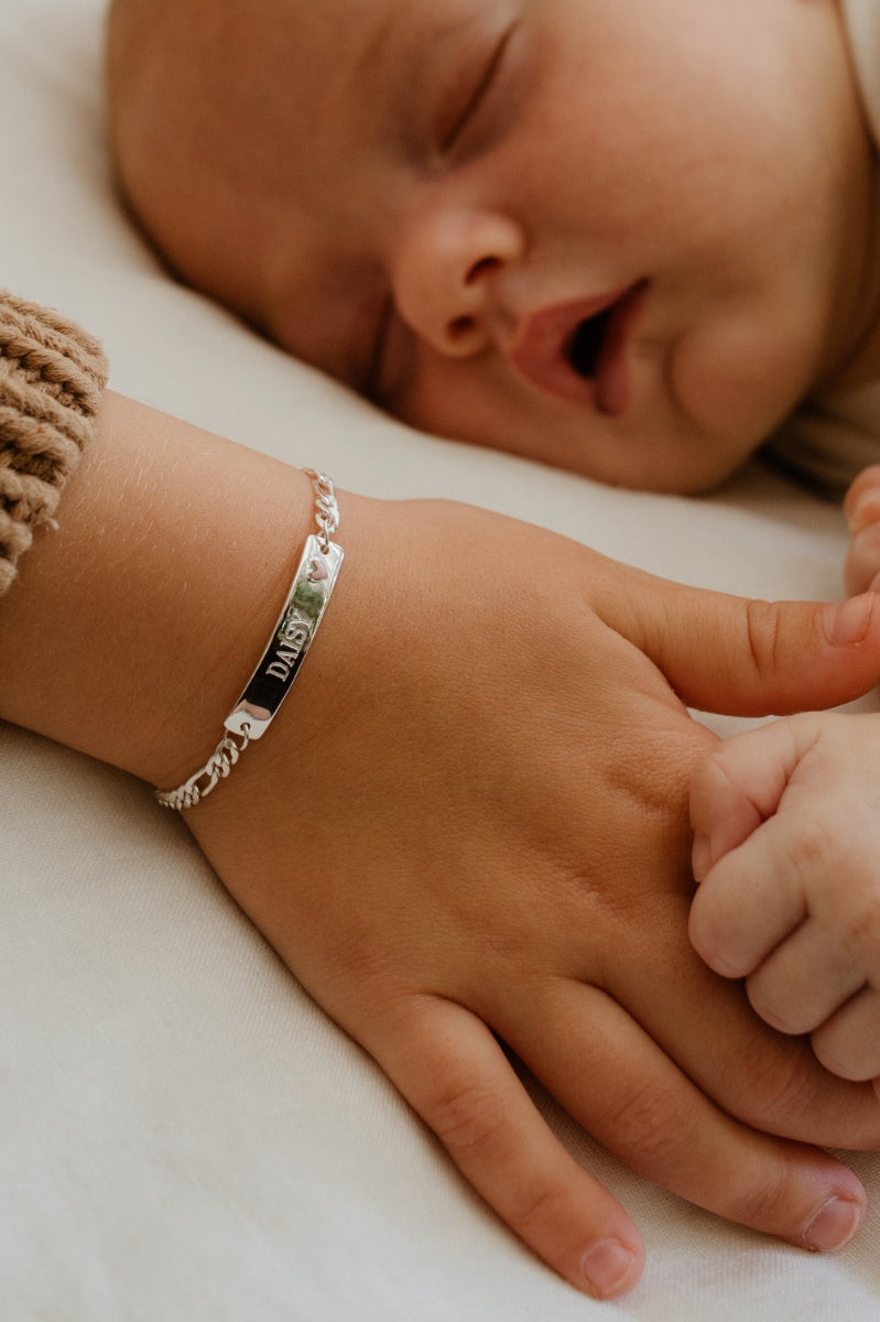 A child is wearing the Pink Darling Bracelet with personalised engraving on it by Bluebird Jewellery.