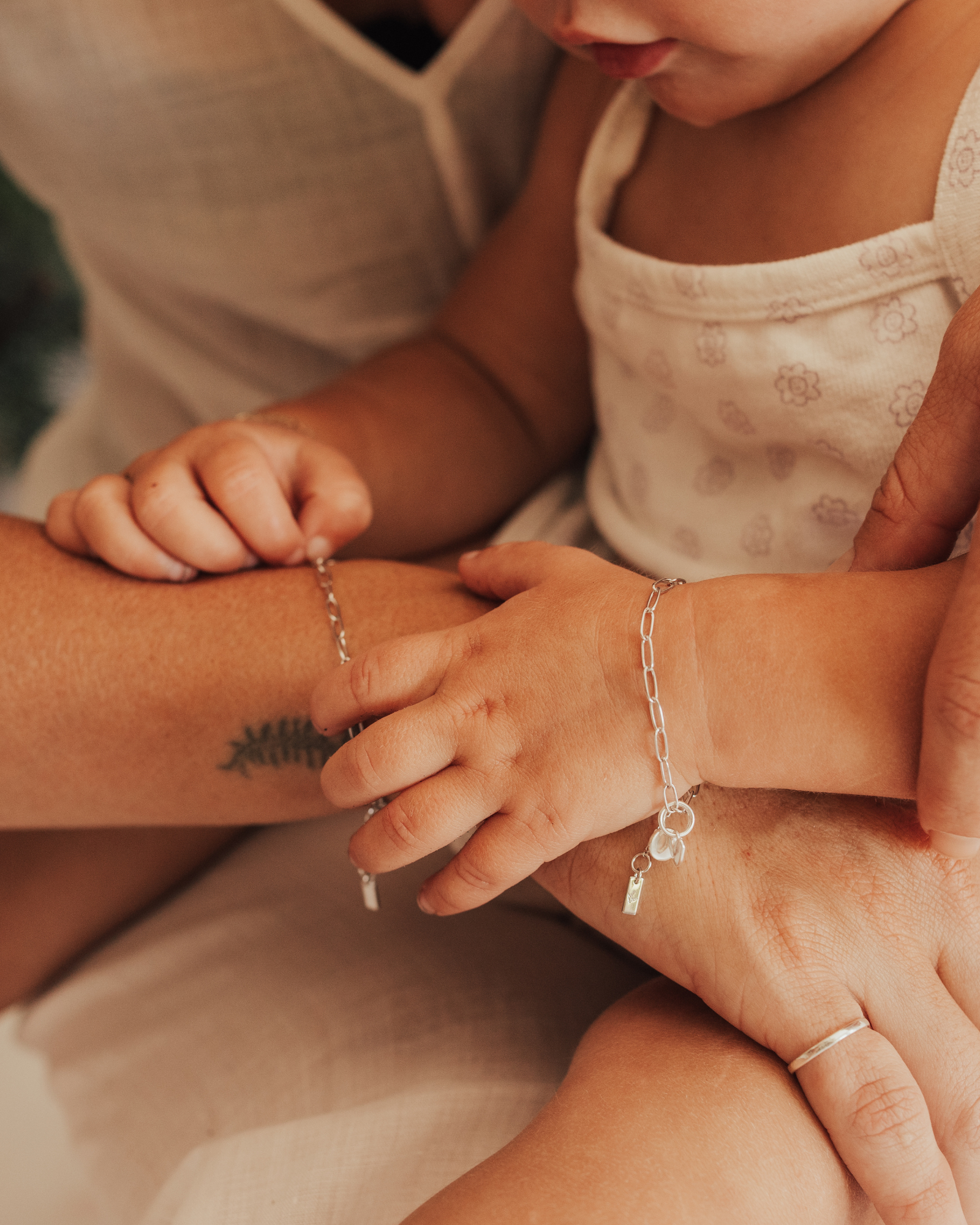 A close-up of a mum and baby wearing matching Posie Bracelets, symbolising love and connection through personalised fine jewellery by Bluebird Co