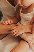 A close-up of a mum and baby wearing matching Posie Bracelets, symbolising love and connection through personalised fine jewellery