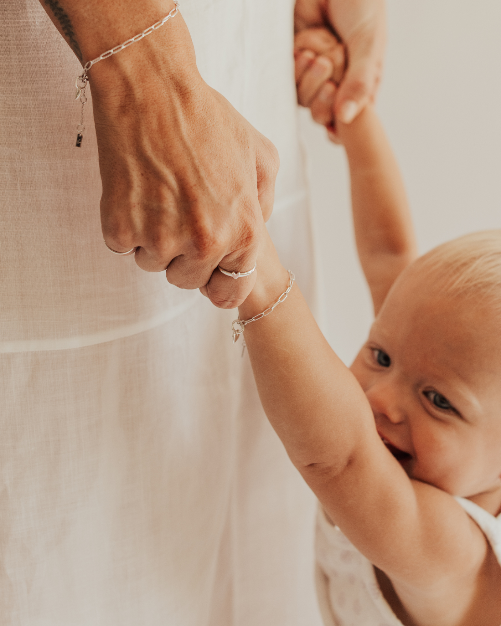 A close-up of a mum and baby wearing matching Posie Bracelets with heart charms designed as elegant fine jewellery pieces symbolising love and connection by Bluebird Jewellery.