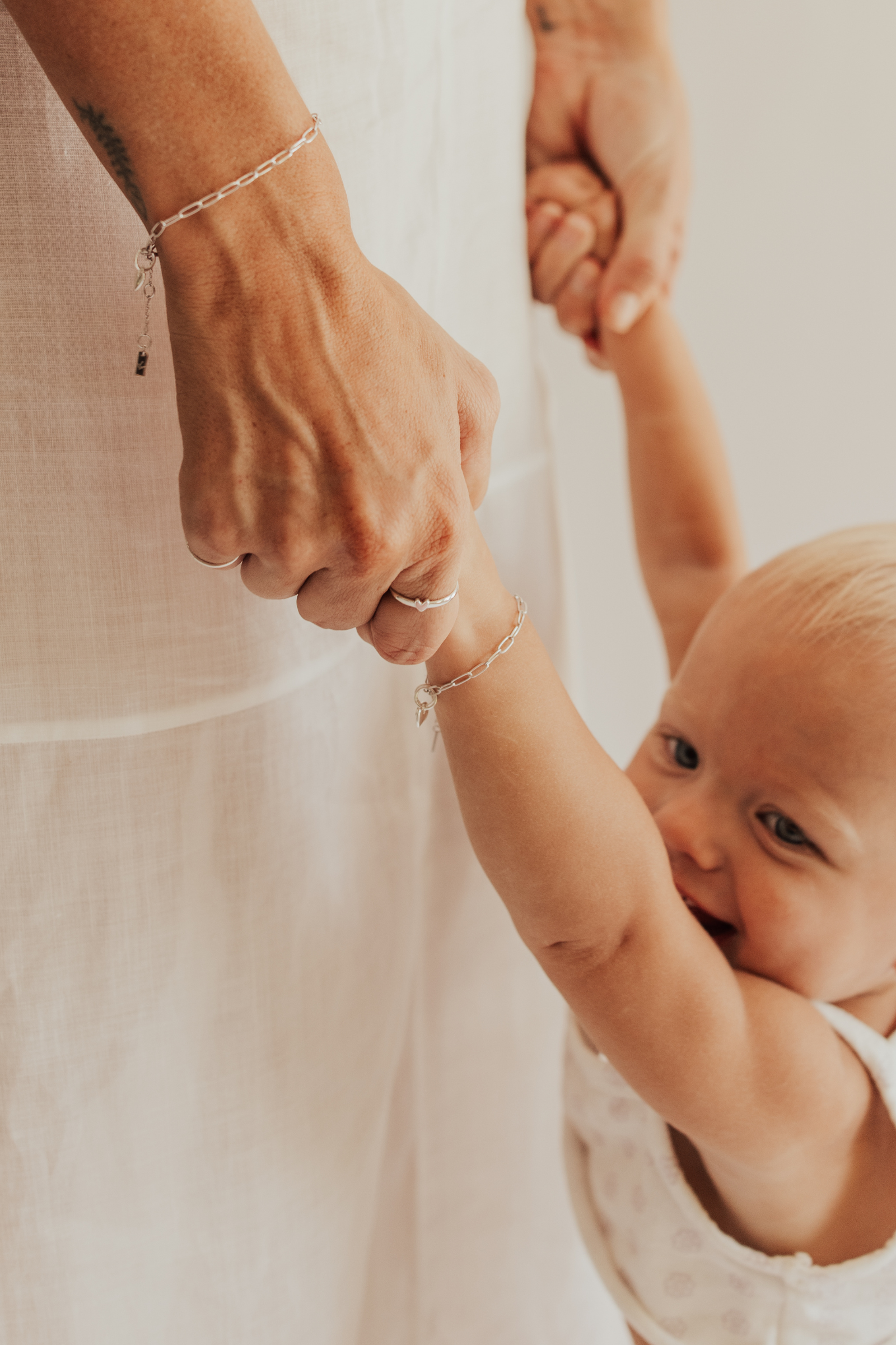 A close-up of a mum and baby wearing matching Posie Bracelets with heart charms designed as elegant fine jewellery pieces symbolising love and connection.
