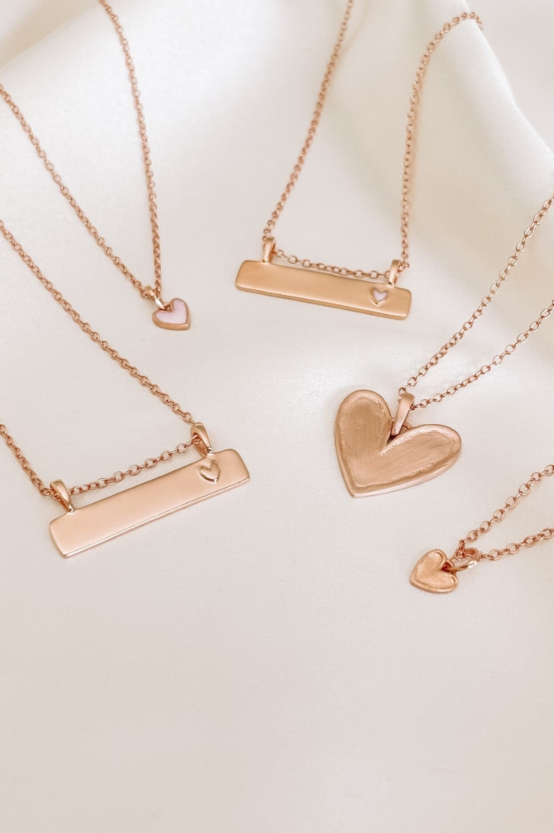 Engraved rose gold necklaces with heart and bar pendants, keepsake gifts designed to be treasured for a lifetime.
