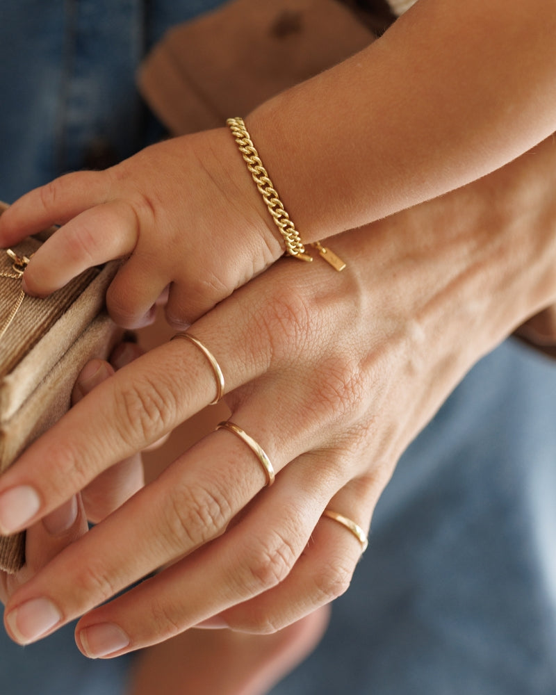 A 2mm Signature Ring in size 7 is worn on a woman's middle finger and is placed next to the 1.5mm Signature Ring and 2mm Pinky ring.