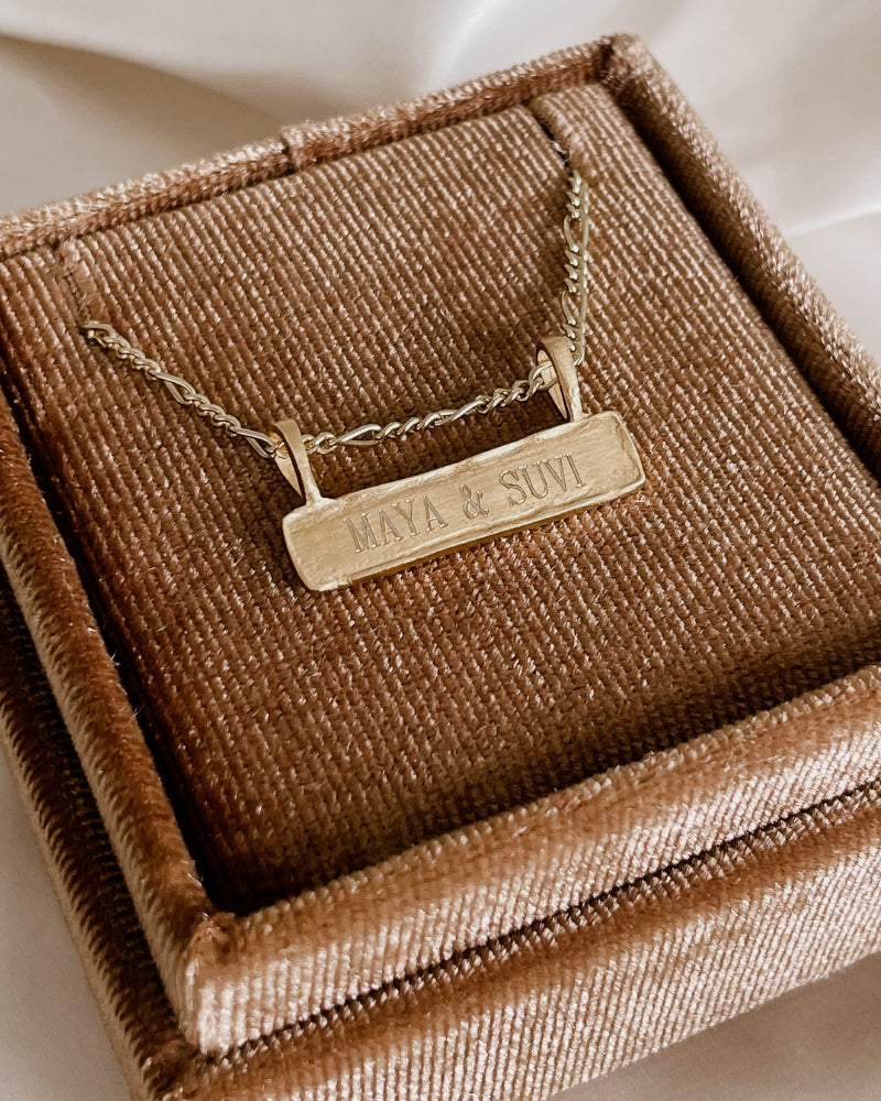 A close up look at the Signature Bar Necklace resting inside a velvet Bluebird Co gift box.