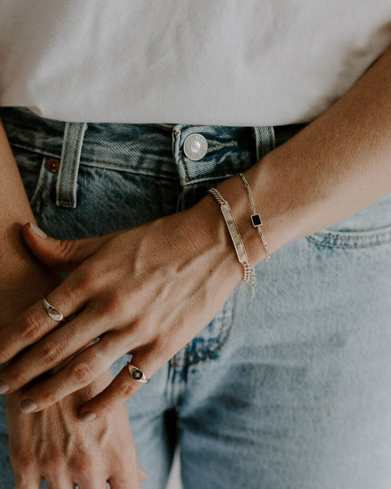 A close up of the Signature Bracelet in child size worn by an adult alongside the Loved Bracelet by Bluebird Jewellery.