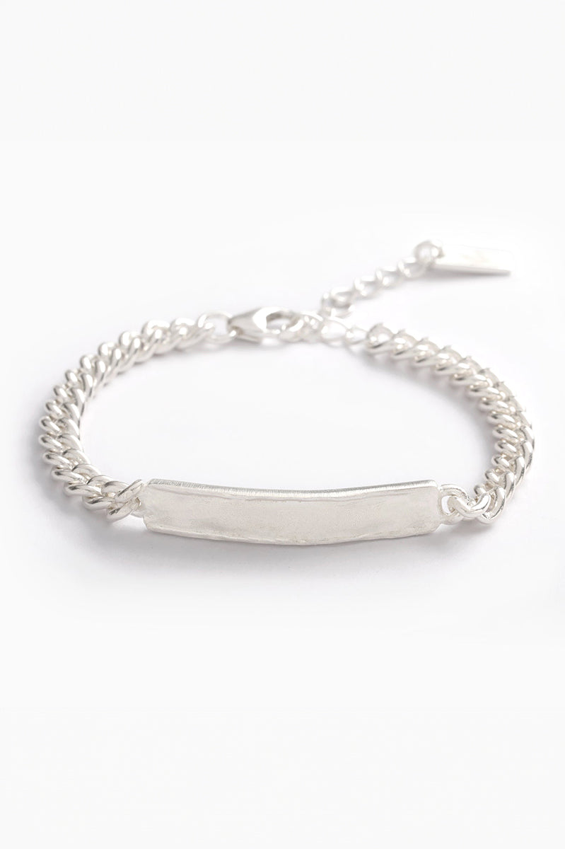 Close-up of silver signature bracelet with engraved plate and adjustable chain on white background