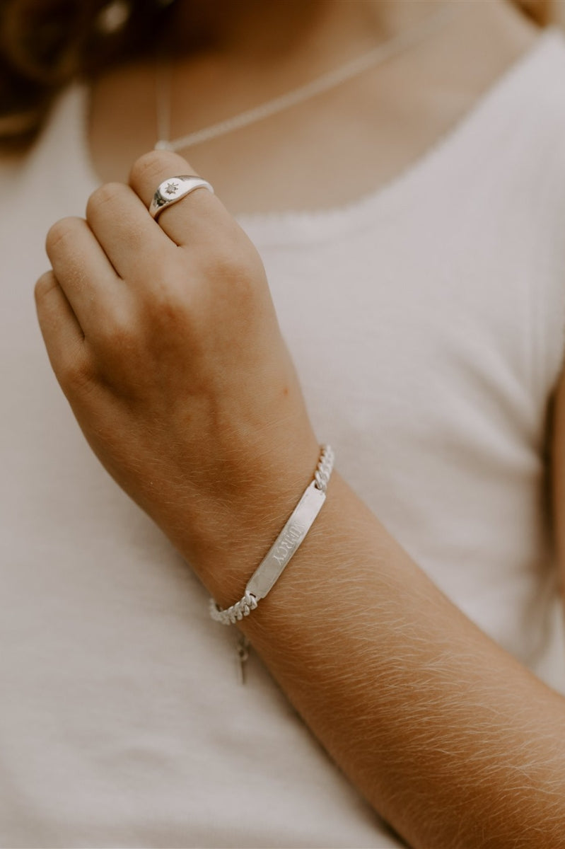 Child wearing engraved signature silver bracelet, paired with silver signet ring by Bluebird Jewellery.