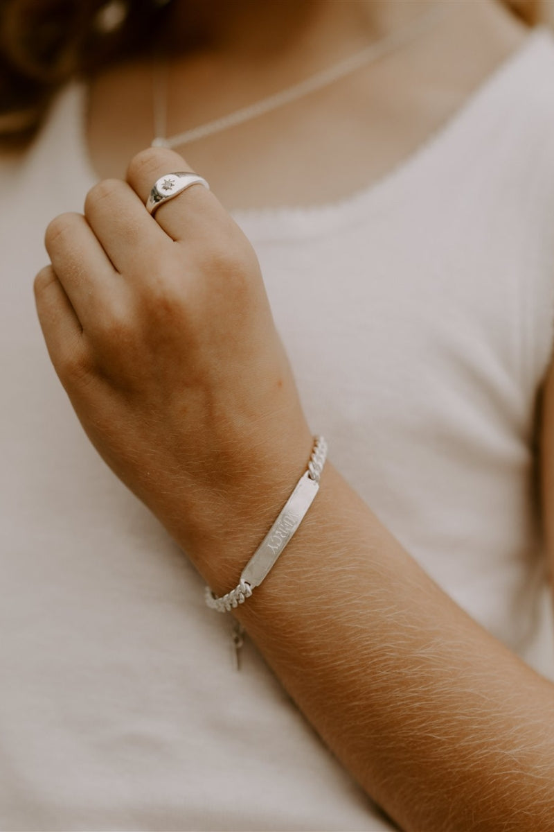 Child wearing engraved signature silver bracelet, paired with silver signet ring by Bluebird Jewellery.