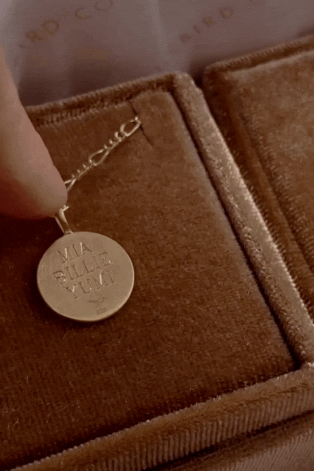 The signature necklace in gold displays the 3 names that are engraved on the back and a name on the front.