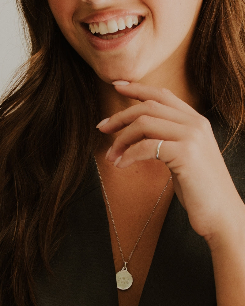 A woman is wearing a silver Pinky Ring with engraving inside it