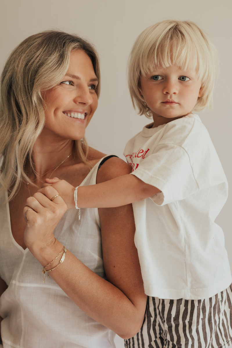A mother is smiling at her son who is wearing a personalised signature bracelet with personalised engraving on it.  This Bluebird Bracelet is part of the Signature Collection and is made from solid sterling silver.