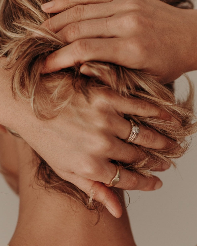 A detailed image showing a woman’s hands wearing minimalist gold rings, symbolising understated luxury and modern style by Bluebird Jewellery