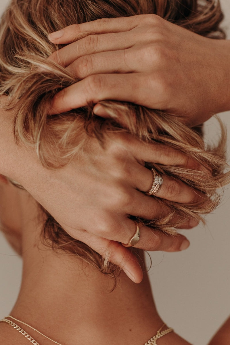 A detailed image showing a woman’s hands wearing minimalist gold rings, symbolising understated luxury and modern style by Bluebird Jewellery