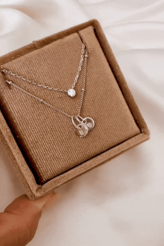 A Silver Lume Necklace sits in a gift box with a Petite Personalised Necklace with two persojnalised initial pendants. The two necklaces compliment each other and offer a lovely layered necklace look.