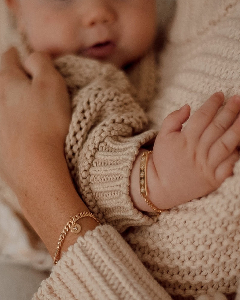 A tender image of a mother and child wearing Single Pearl Bracelet and Vintage Pearl Bracelet, symbolising love and connection by Bluebird Jewellery.