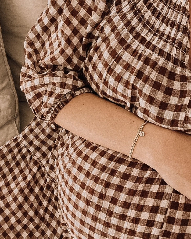 A pregnant woman wearing an elegant gold Cuban Link Chain with a single vintage pearl pendant, symbolising grace and connection by Bluebird Jewellery.