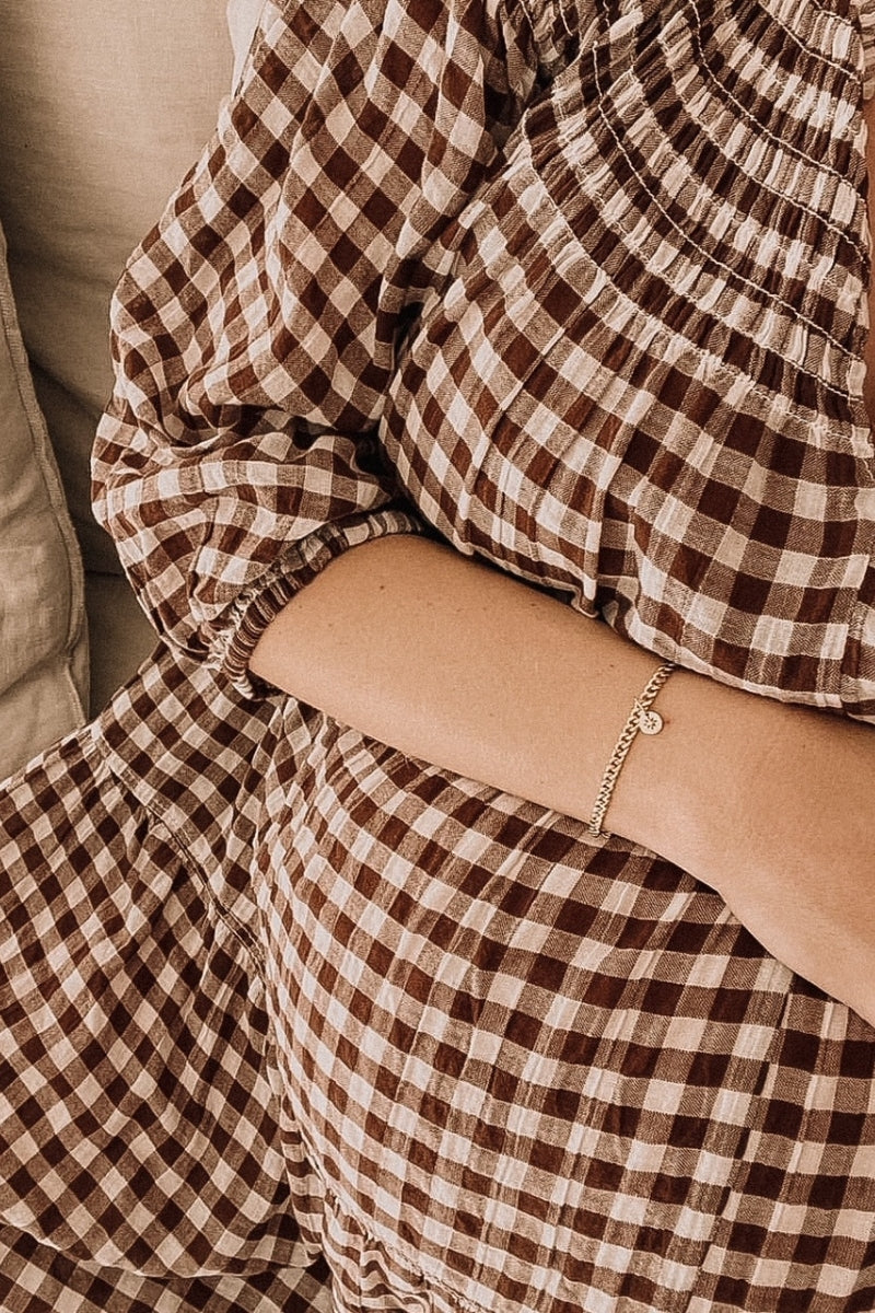 A pregnant woman wearing an elegant gold Cuban Link Chain with a single vintage pearl pendant, symbolising grace and connection.