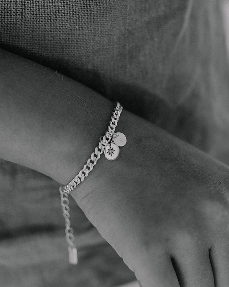 A child wearing a Cuban Link Chain with a single vintage pearl pendant with a personalised solid gold initial pendant, crafted in elegant fine jewellery by Bluebird Co