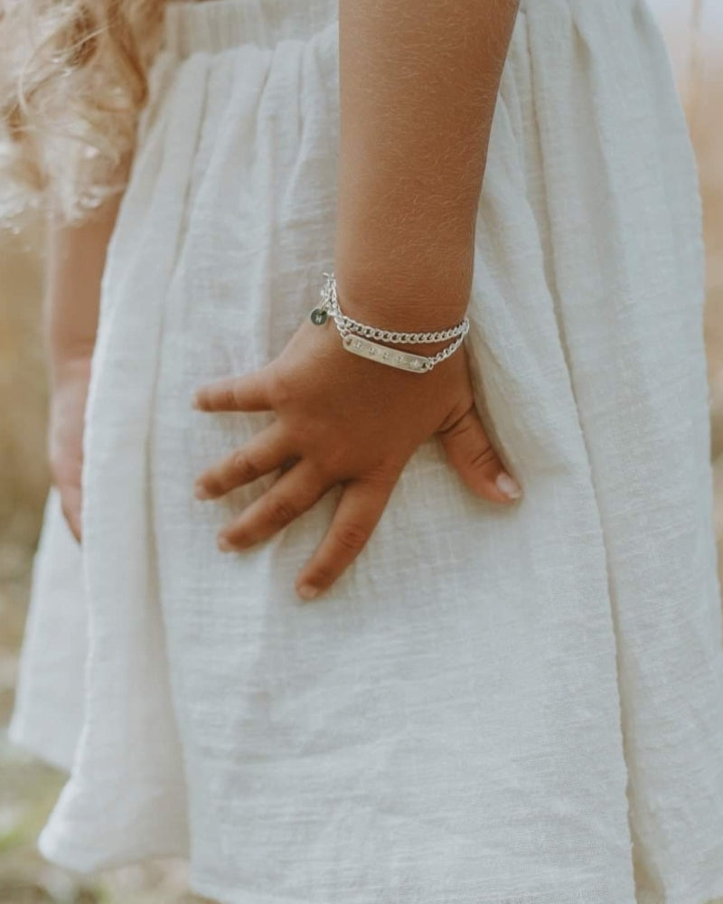 A detailed image of a young child wearing a Cuban Link Chain Necklace with a vintage pearl pendant and matching pearl bracelet, designed as a timeless keepsake.