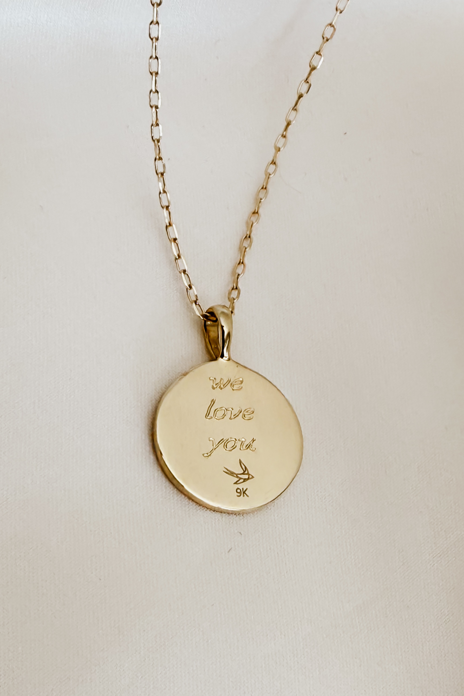 A detailed close-up of the Soléil Pendant in 9ct gold, designed with a round, sun-inspired shape with engraving "We love you" for timeless personalisation.