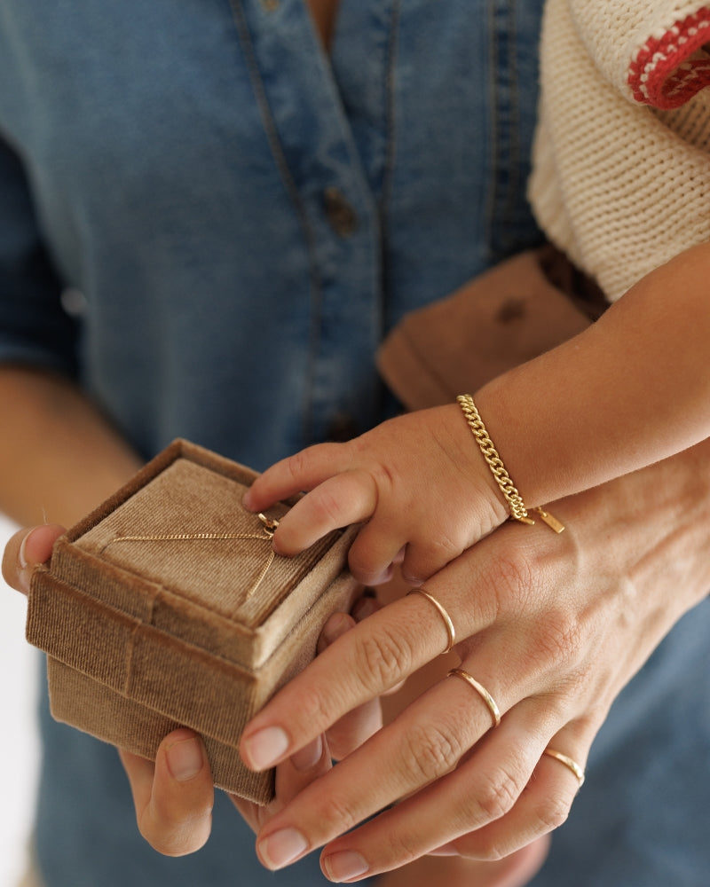 A close-up of the Solid Gold Bracelet, signature rings and gold cuban chain bracelet by Bluebird Jewellery, crafted in fine gold as a personalised piece for both casual and refined occasions.
