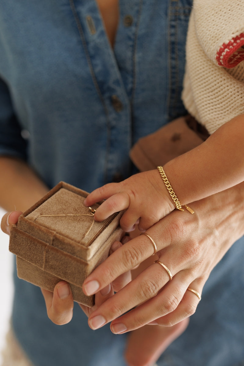 A close-up of the Solid Gold Bracelet, signature rings and gold cuban chain bracelet by Bluebird Jewellery, crafted in fine gold as a personalised piece for both casual and refined occasions.