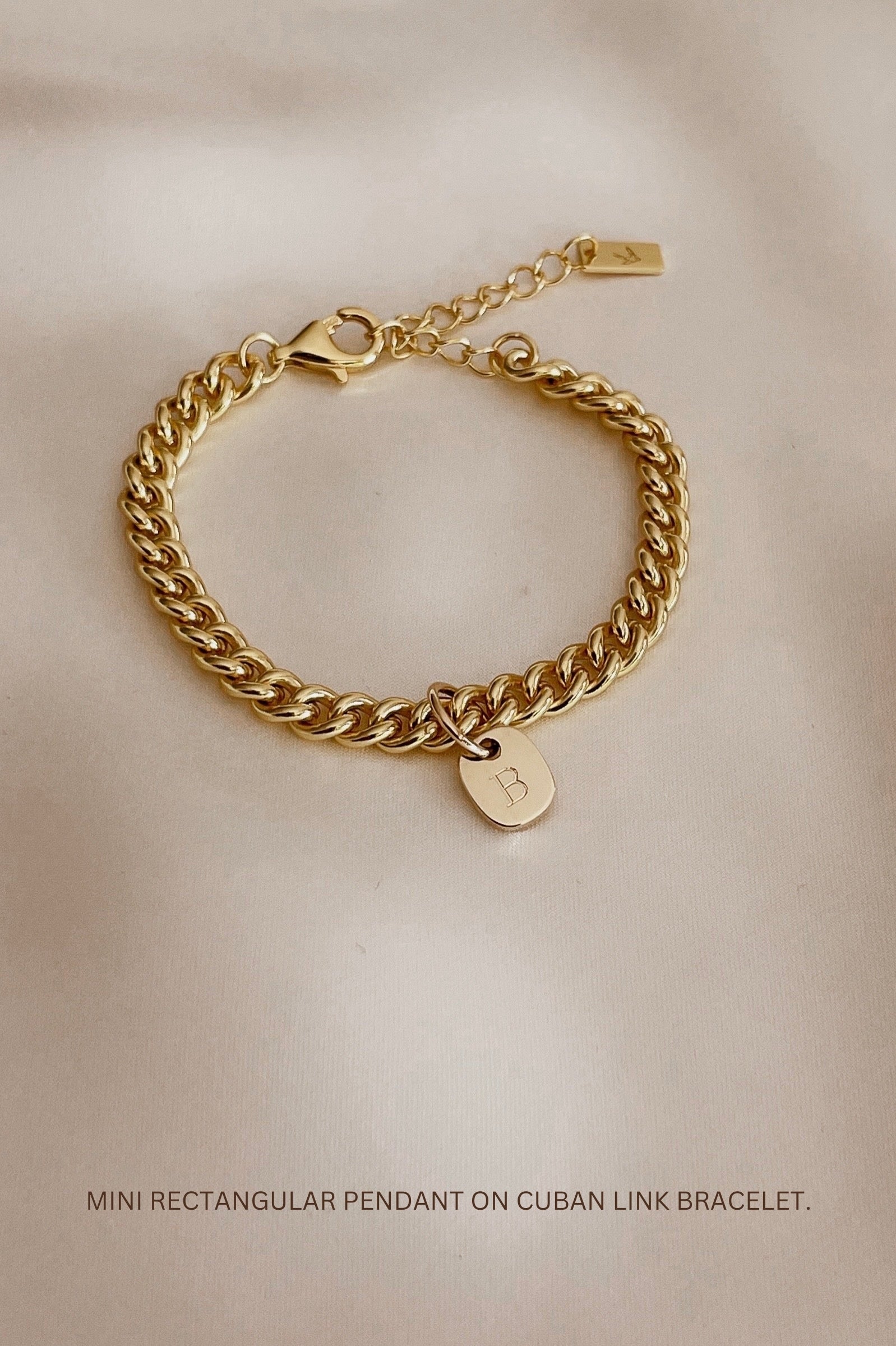 The Cuban Chain Bracelet with Mini Rectangular Pendant by Bluebird Jewellery features gentle curves and a luxe, modern silhouette. Personalised with your chosen letter, it embodies feminine elegance and can be worn beautifully on any necklace, bracelet, or anklet chain.