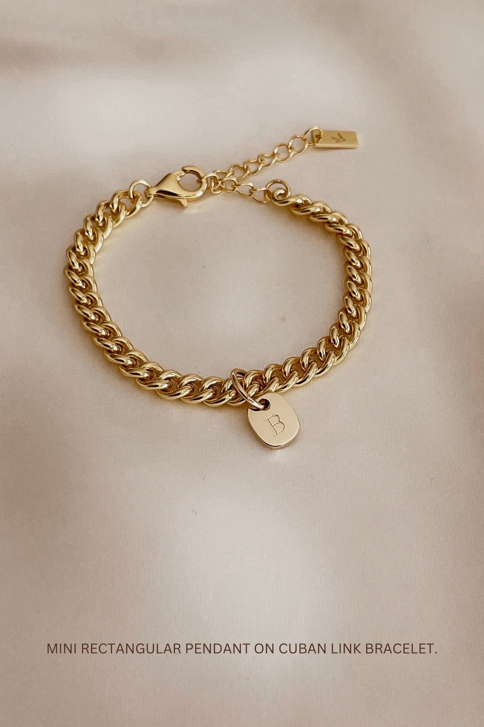 The Cuban Chain Bracelet with Mini Rectangular Pendant by Bluebird Jewellery features gentle curves and a luxe, modern silhouette. Personalised with your chosen letter, it embodies feminine elegance and can be worn beautifully on any necklace, bracelet, or anklet chain.
