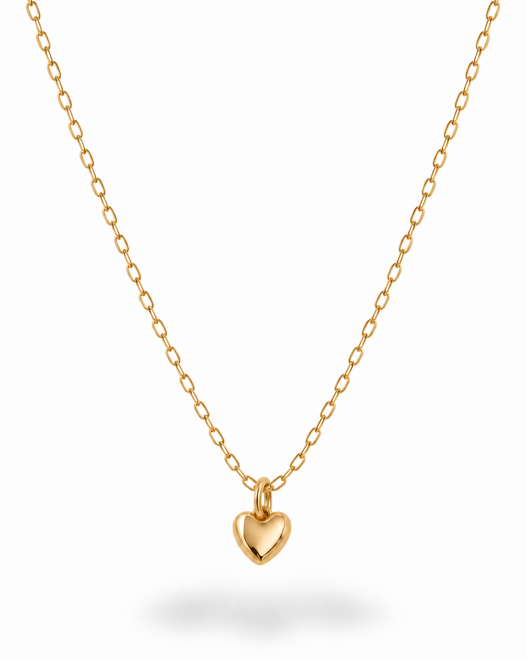 A delicate gold chain necklace with a small, polished gold heart pendant, displayed against a clean white background with a soft shadow underneath.