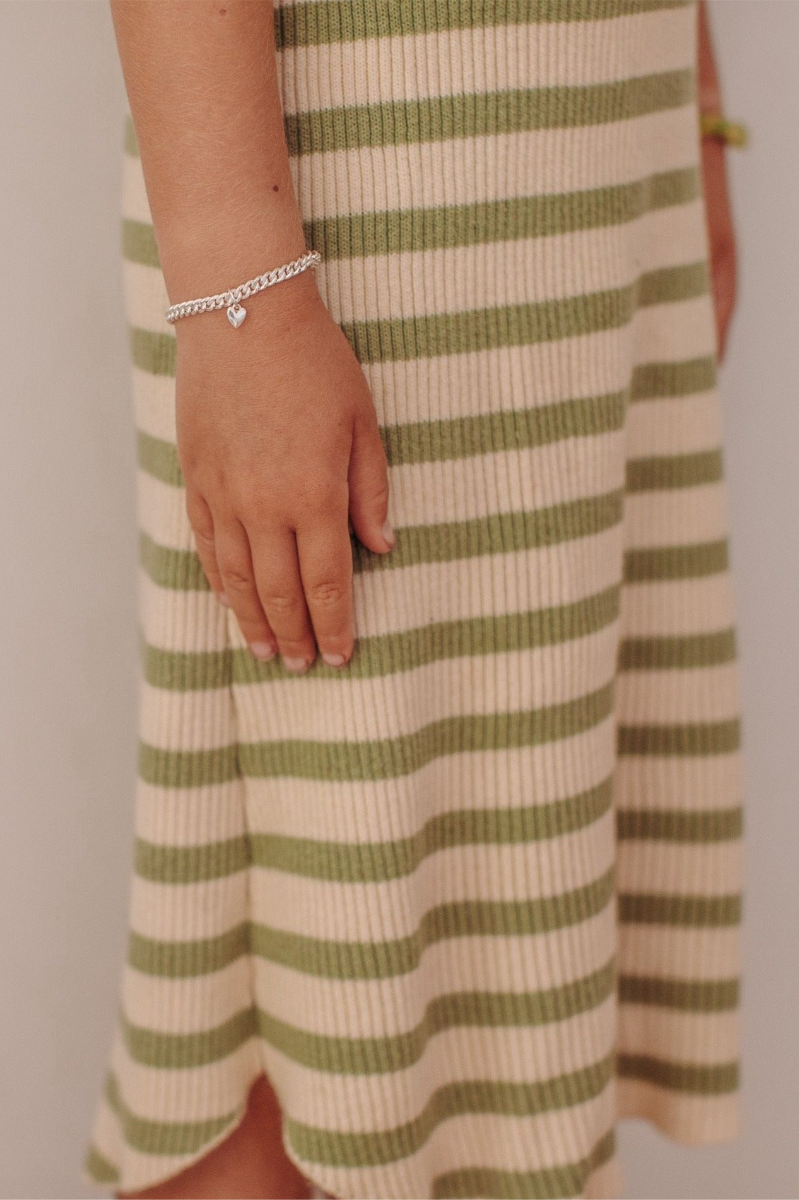 A mini sweetheart pendant rests on a cuban link bracelet chain and is worn by a child. matching baby and adult sizes are also available by Bluebird Jewellery