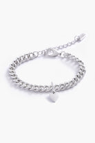 A minimalist silver bracelet with a heart charm, photographed on a white background to showcase its craftsmanship and simplicity.