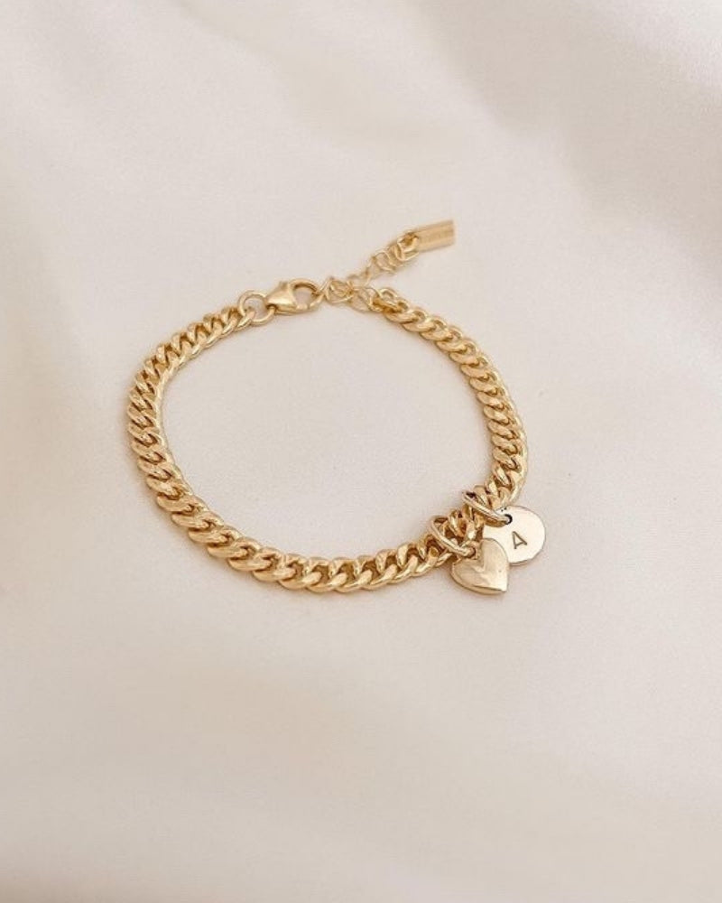 A Sweetheart Cuban Link Chain Bracelet featuring a polished heart charm and personalised soild gold initial pendant, crafted as a meaningful fine jewellery piece.