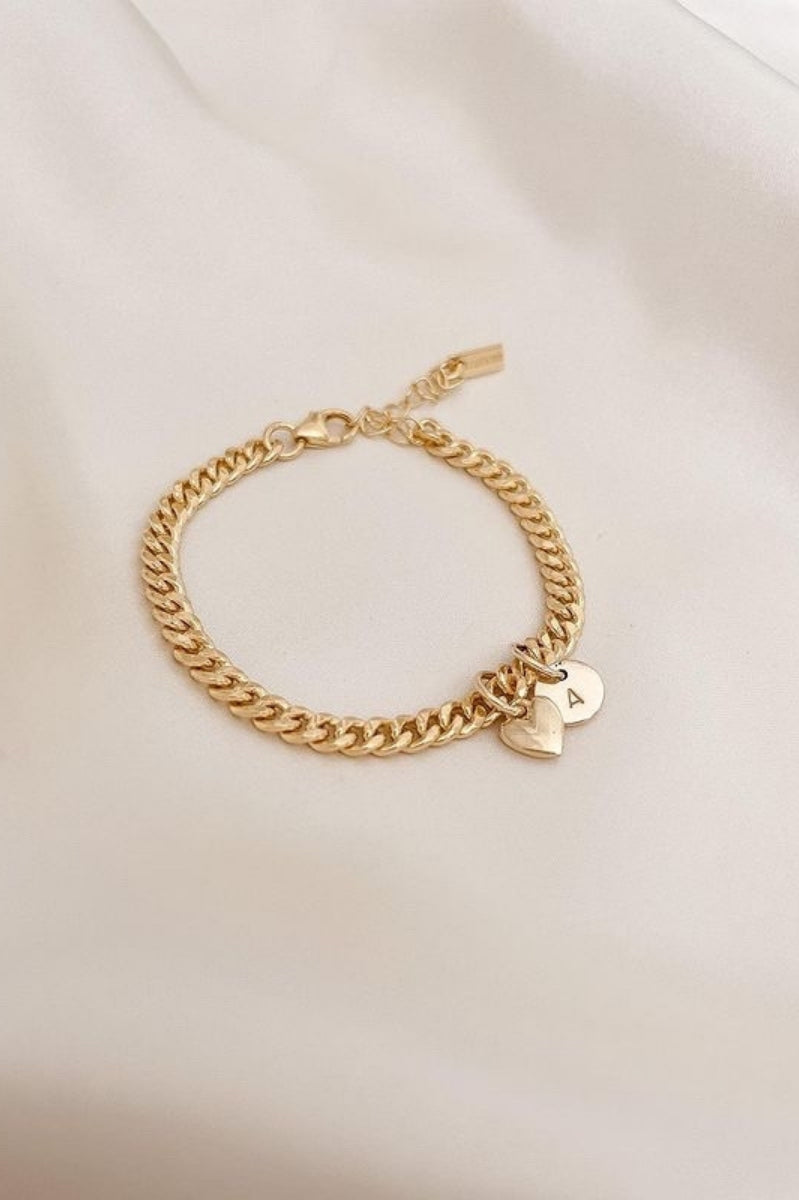 A Sweetheart Cuban Link Chain Bracelet featuring a polished heart charm and personalised soild gold initial pendant, crafted as a meaningful fine jewellery piece.