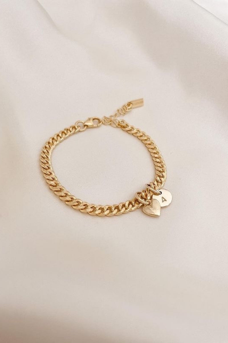 A Sweetheart Cuban Link Chain Bracelet featuring a polished heart charm and personalised soild gold initial pendant, crafted as a meaningful fine jewellery piece.