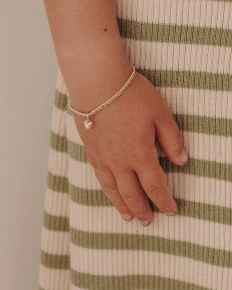 A child wearing a Sweetheart Lace Chain Bracelet featuring a single heart charm on a delicate gold chain, crafted in timeless fine jewellery style by Bluebird Co