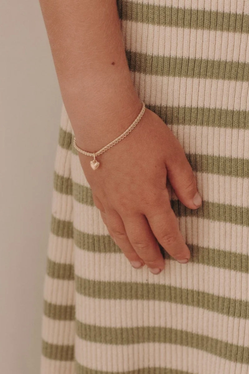 A child wearing a Sweetheart Lace Chain Bracelet featuring a single heart charm on a delicate gold chain, crafted in timeless fine jewellery style by Bluebird Co