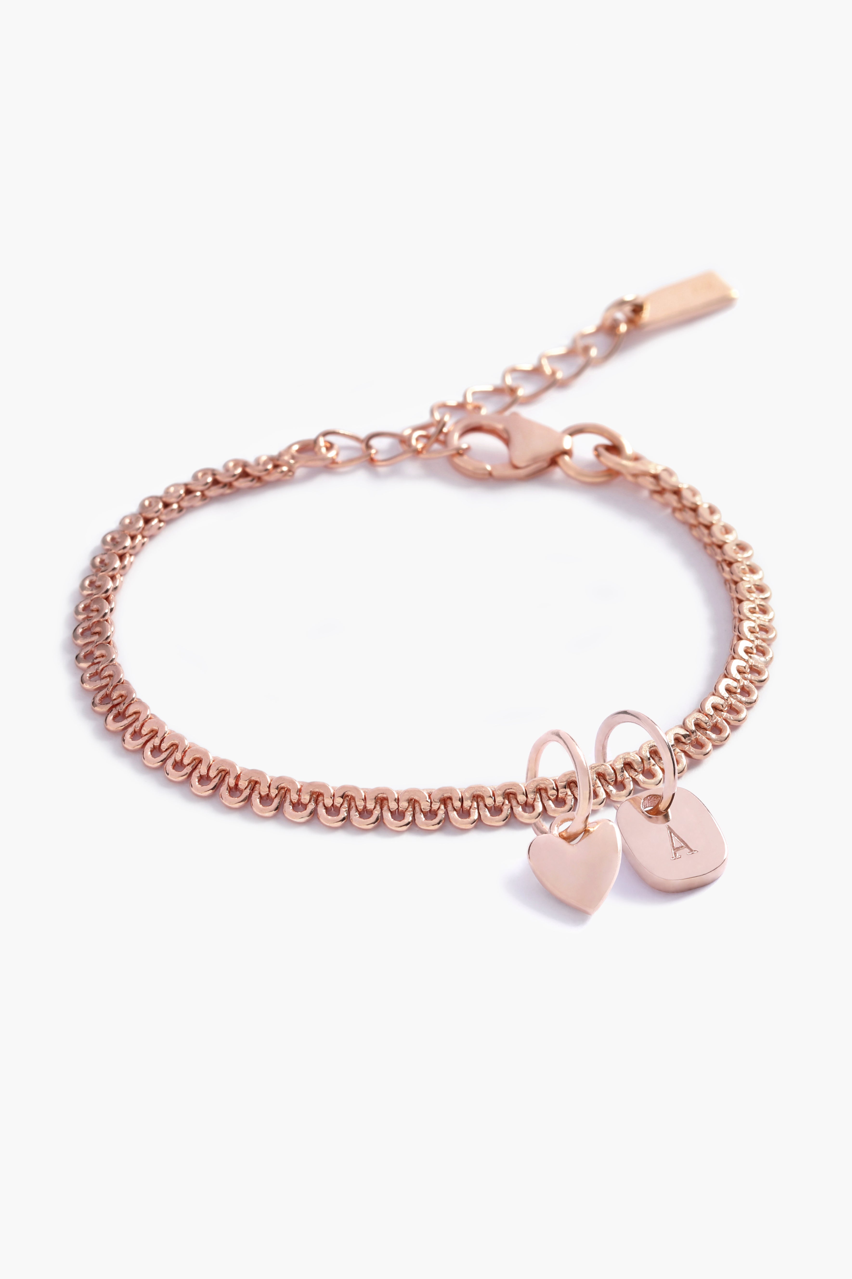 A close-up of a rose gold Lace Chain Bracelet adorned with a heart charm and personalised soild rose gold rectangular initial pendant, crafted as a meaningful keepsake piece by Bluebird Jewellery
