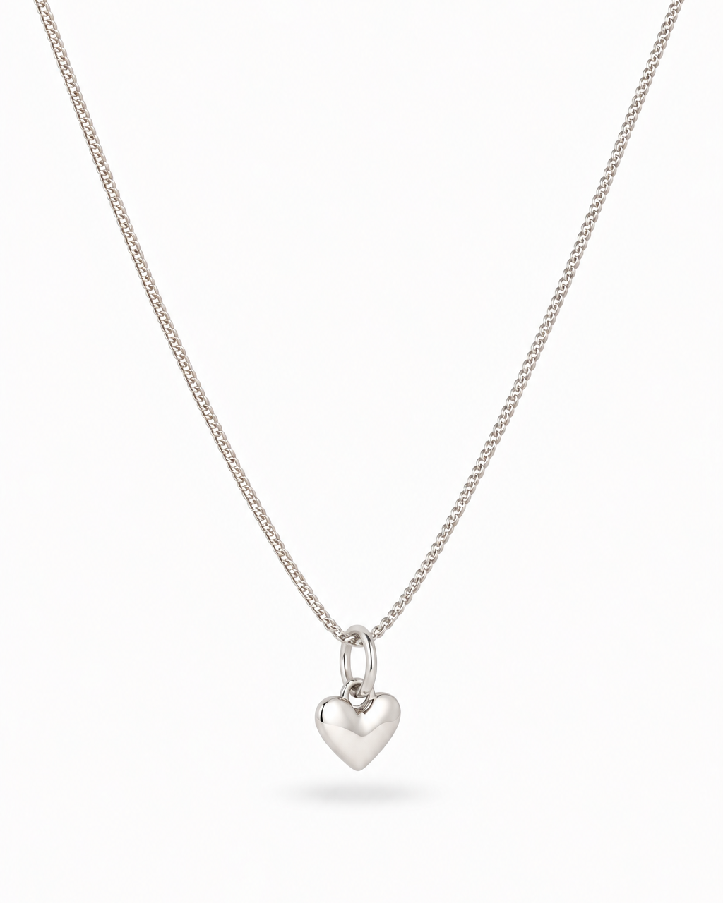 A delicate silver chain necklace with a small, polished heart-shaped pendant, displayed against a clean white background.