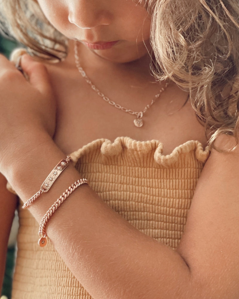 A close-up image of a child wearing the Darling Heart Bracelet by Bluebird Jewellery, showcasing five petite heart details within a refined and timeless gold chain.