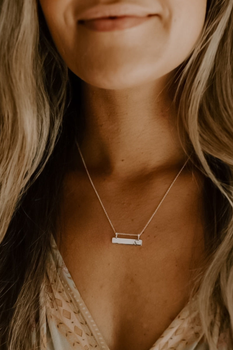 Adult wearing engraved Darling Bar Necklace in silver with heart detail on delicate silver chain