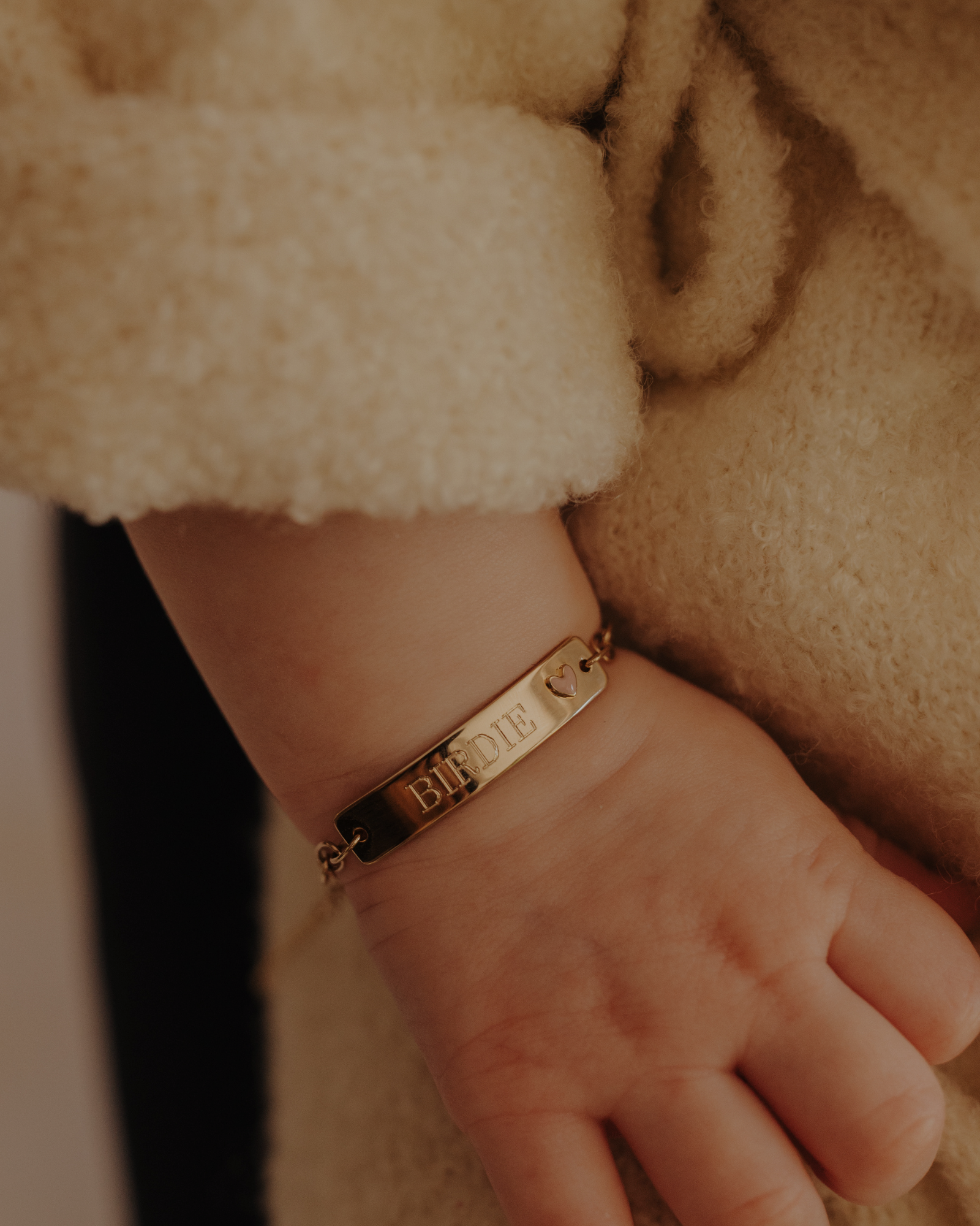 Baby wrist with engraved 9ct solid gold Pink Darling Bracelet featuring heart charm. Bluebird Jewellery.