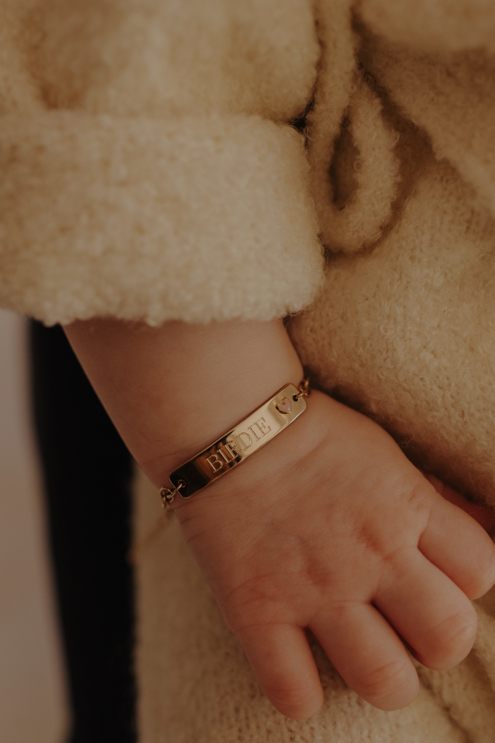 Baby wrist with engraved 9ct solid gold Pink Darling Bracelet featuring heart charm. Bluebird Jewellery.