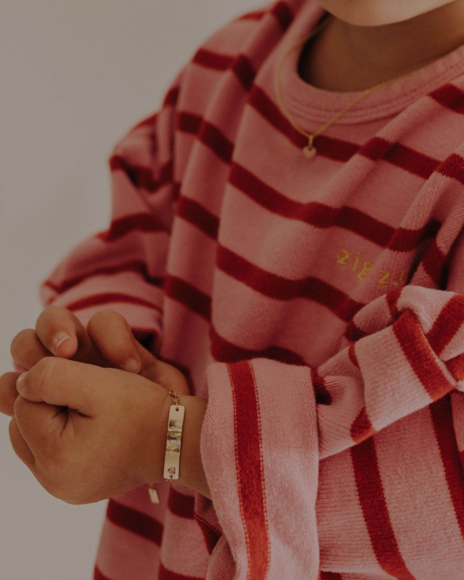 Toddler wearing 9ct solid gold Pink Darling Bracelet with heart detail. Bluebird Jewellery.