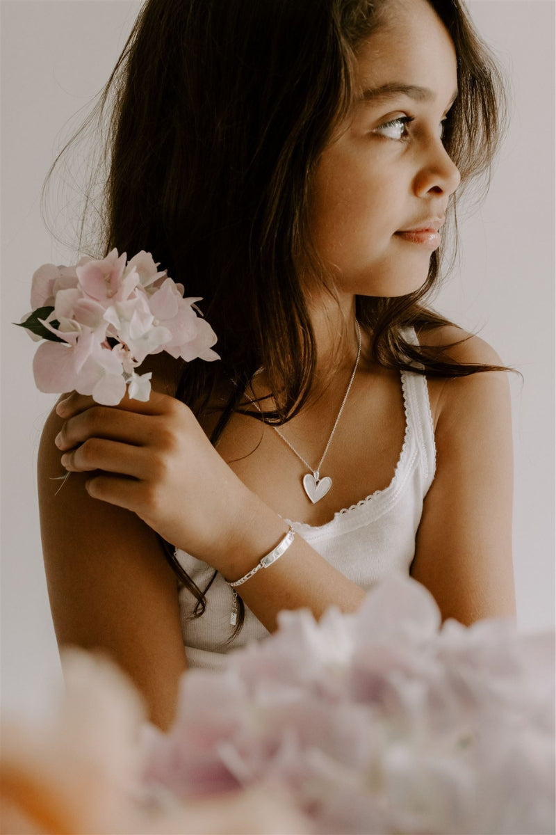 A young girl is wearing the Silver Darling Necklace with heart pendant, a delicate personalised jewellery piece