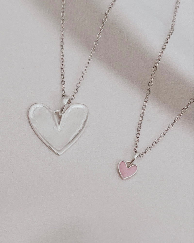 Silver heart pendant necklace paired with petite pink darling heart necklace.