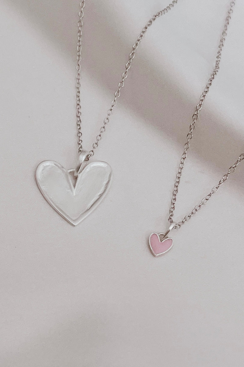 Silver heart pendant necklace paired with petite pink darling heart necklace.